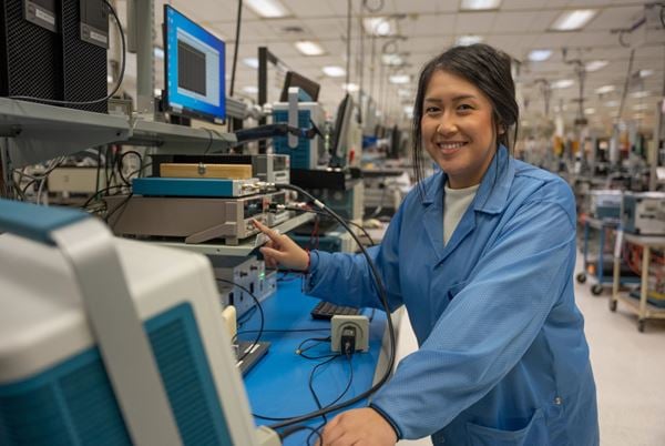 Female lab technician calibrating bench instruments including an oscilloscope