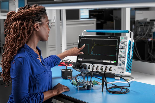 Female engineer using a Tektronix oscilloscope, shown with attached probes and device under test (DUT)