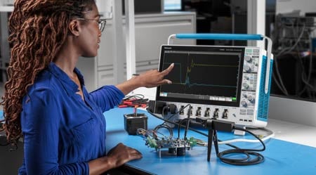 Ingenieur verwendet ein Tektronix-Oszilloskop und einen Oszilloskop-Tastkopf zur Messung eines Signals an einem zu prüfenden Gerät