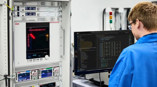 engineer working at a PC in front of a a test system with two MP500s a switch matrix and other test and measurement instrumentation