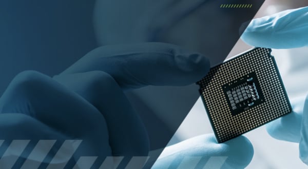 A semiconductor technician in a cleanroom suit holding a square computer processor between their fingers